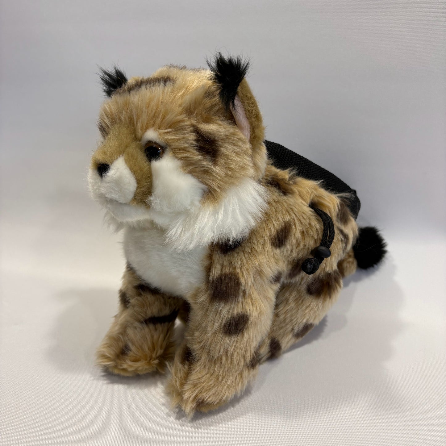 Bobcat plush rock climbing chalk bag shown in a sitting position, showing unique climbing gear for kids and women. Background is white